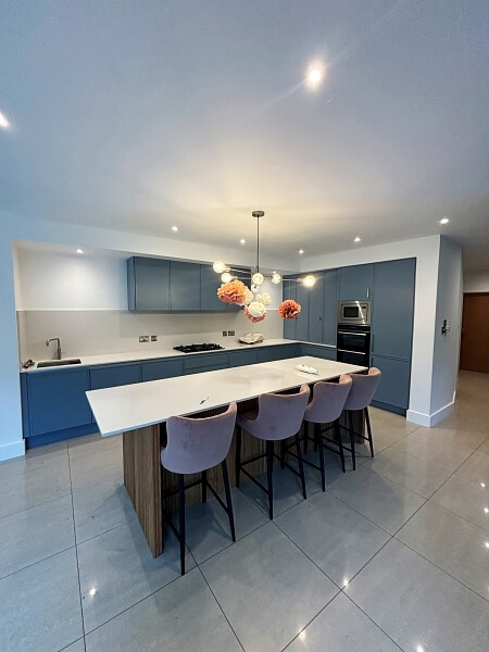 Kitchen with blue hand painted island with a white top and blue painted cupboards with white walls in the background by Impressions Expert Kitchen Painters Dublin