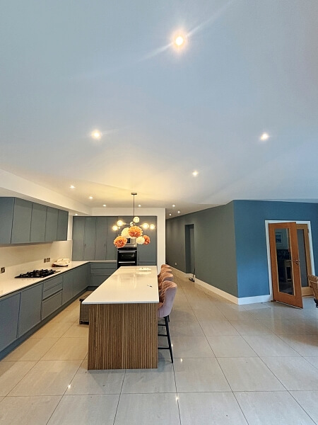 Kitchen with blue hand painted island with a white top in the centre and blue painted cabinets with white walls on the left and blue wall on the right by Dublin kitchen painters