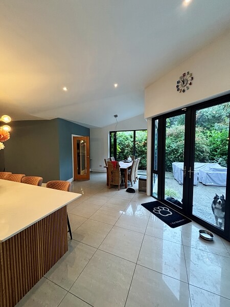 Floor to ceiling glass doors on the right and part of a hand painted kitchen island in the right foreground and blue wall painted by Impressions Dublin kitchen painters in the back left