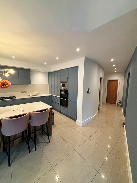 Partial view of a hand painted blue kitchen island on the left with painted blue cupboards in the background on the left and centre by Impressions painting and decorating Dublin. Corridor to brown door on the right