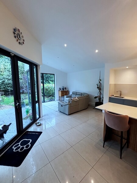 Floor to ceiling glass doors on the left and part of a hand painted kitchen island on the right and white walls with sofa in the centre - all painted by Impressions Dublin kitchen painters in the back left